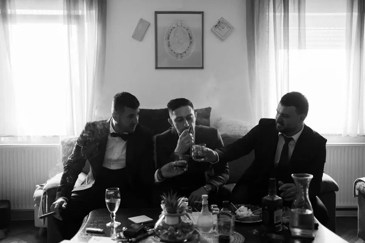 Kum i prijatelji mladoženje opušteno se druže uz piće i cigare prije vjenčanja.