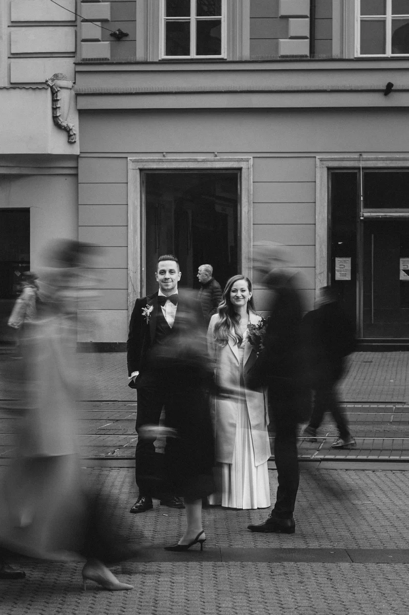Mladenci stoje zagrljeni u središtu Zagreba dok ljudi prolaze oko njih – trenutak kao da je vrijeme stalo.